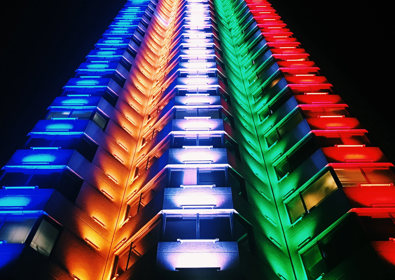 Image of tower block lit up in multi coloured neon lights