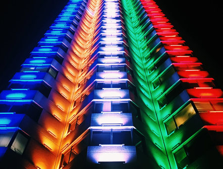 Image of tower block lit up in multi coloured neon lights