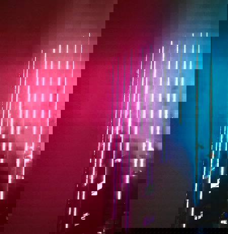 Modern high rise building with blue neon lights vertically along the building front