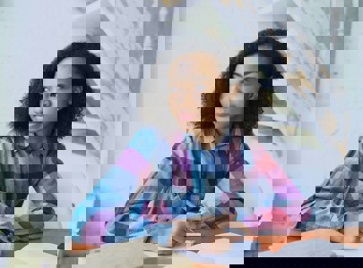 Young girl with pen in her hand staring out the window while studying