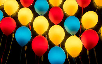 Blue red and yellow balloons floating against a black background