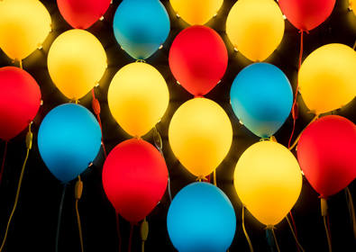 Blue red and yellow balloons floating against a black background