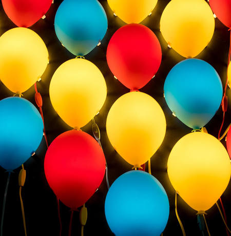 Blue red and yellow balloons floating against a black background
