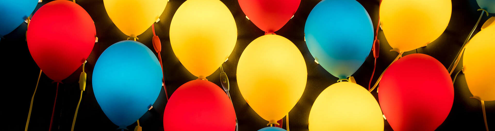Blue red and yellow balloons floating against a black background