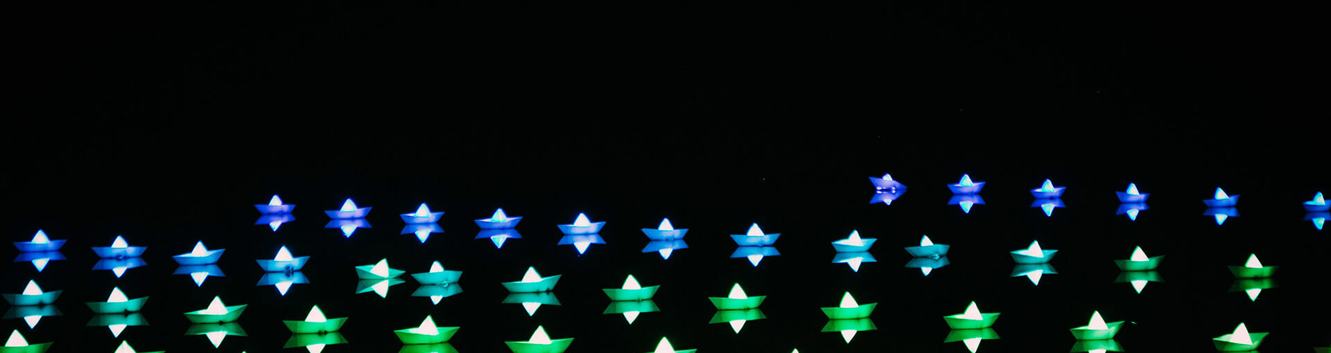Image of neon stars in blue, green and red on a black background