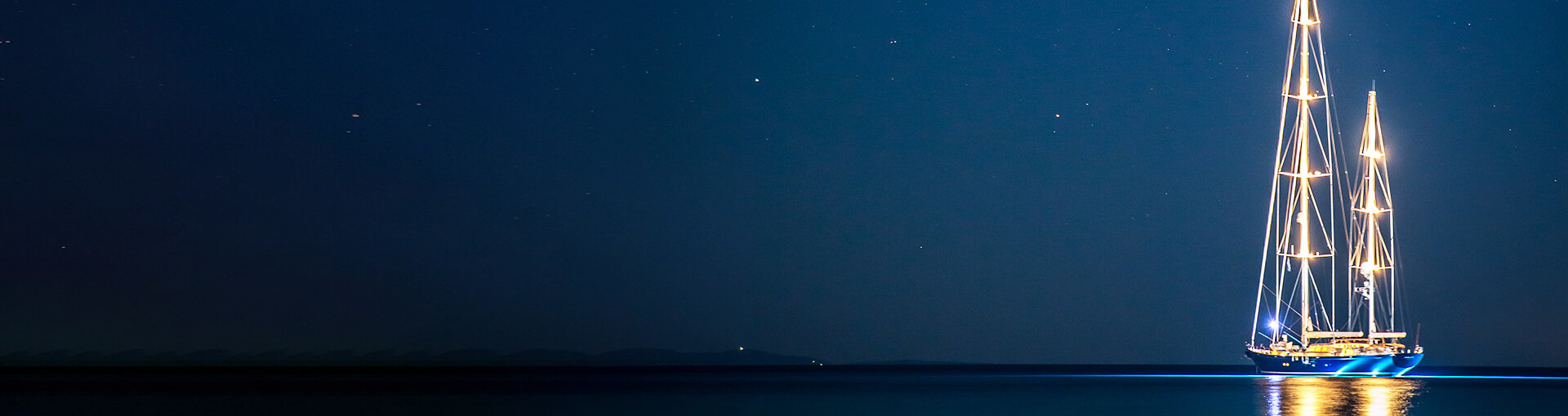 Image of sailing boat on calm sea at night