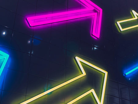 Neon arrows on the side of a building in multiple colours