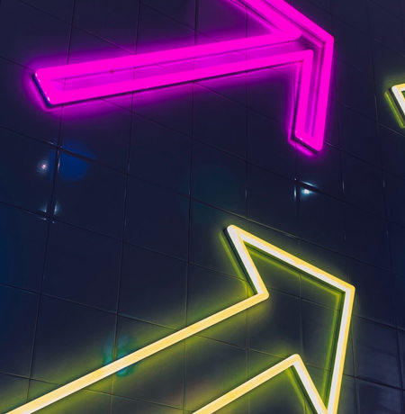 Neon arrows on the side of a building in multiple colours