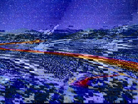 Image of snowy lanscape with car lights lighting up toward the horizon