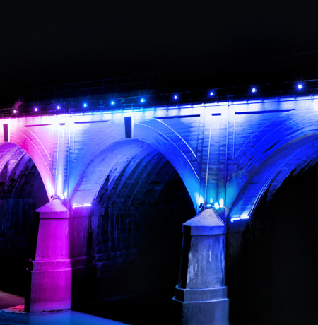 Bridge with blue and purple neon lights lit up at night