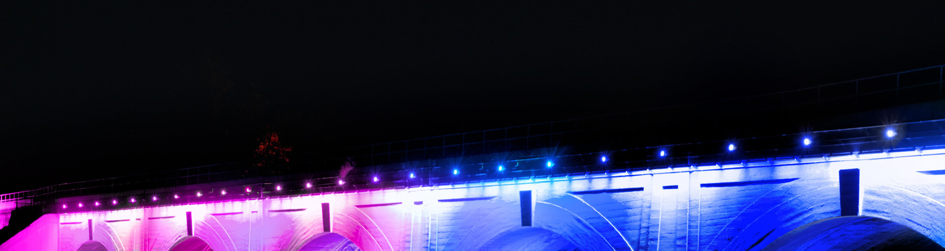 Bridge with blue and purple neon lights lit up at night