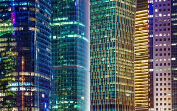 Image of city offices lit up at night in blue and yellow lights