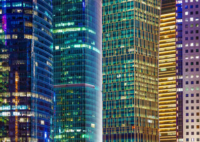 Image of city offices lit up at night in blue and yellow lights