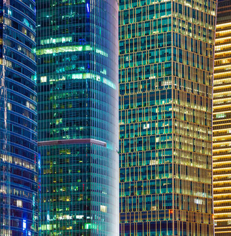Image of city offices lit up at night in blue and yellow lights