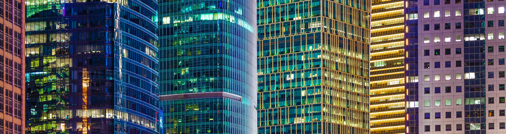 Image of city offices lit up at night in blue and yellow lights