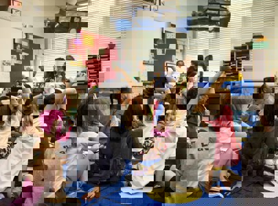 Children in classroom setting with their hands up