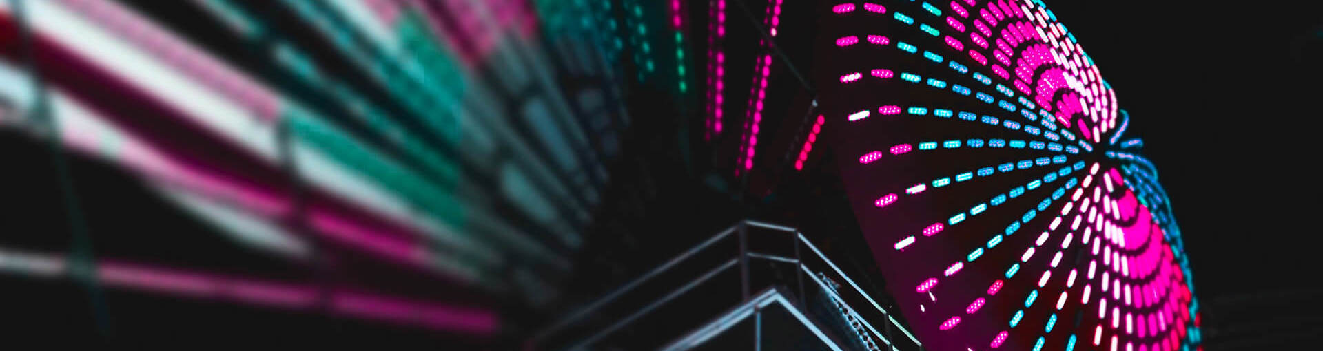 Image from ground looking up at large neon ferris wheel
